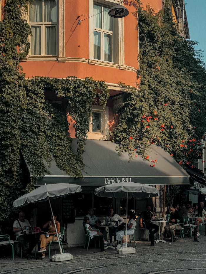 A cozy café nestled against a vine-covered building with people enjoying an al fresco experience.
