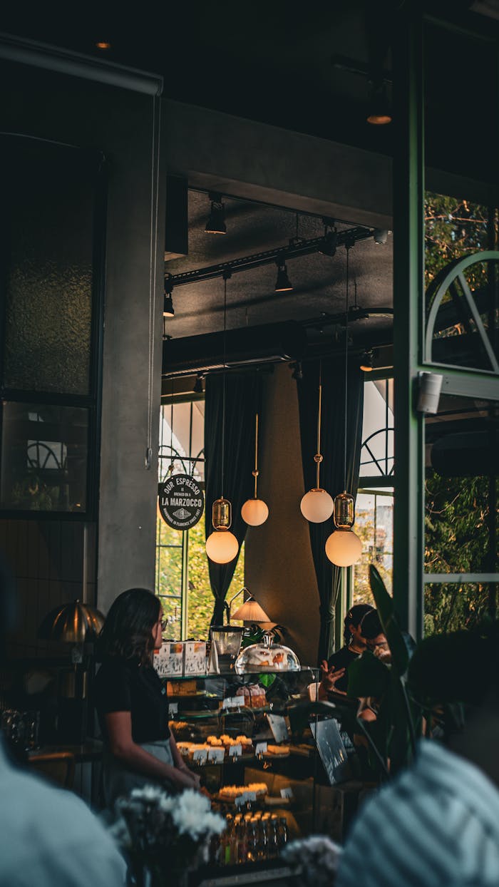 Modern cafe interior with pendant lights and people enjoying coffee.